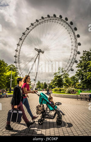 Eine Mutter schiebt einen Kinderwagen vor das Coca-Cola London Eye Stockfoto