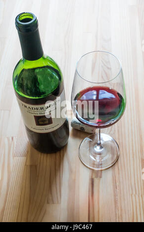 Geöffnete Flasche Trader Joes Cabernet Sauvignon neben einem Glas Wein und den Korken Stockfoto