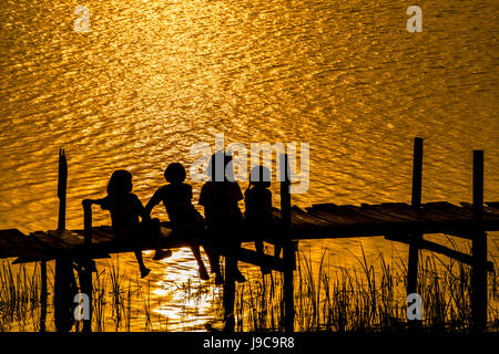 Mädchen sitzen auf der alten Brücke Sonnenuntergang in Riral von Thailand zu sehen Stockfoto