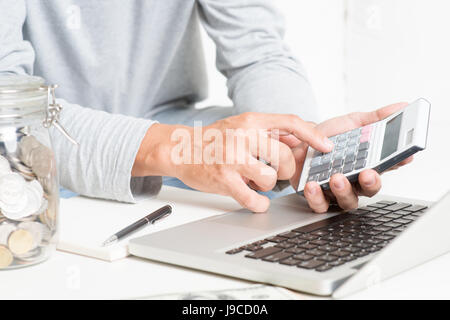 Mann seine Buchhaltung mit Laptop-Computer, Rechner, Tagebuch und Geld zu tun. Finanzberater arbeitet. Stockfoto