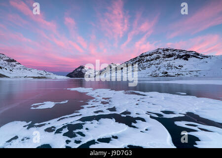 Die gefrorenen Lago Bianco umrahmt von rosa Wolken bei Morgendämmerung, Berninapass, Kanton Graubünden, Engadin, Schweiz, Europa Stockfoto