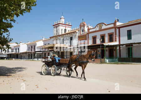 Pferd und Kutsche fahren auf Sand Straßen mit Häusern der Bruderschaft hinter El Rocio, Provinz Huelva, Andalusien, Spanien, Europa Stockfoto
