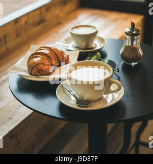 Kaffee Latte, Cappuccino und Croissant auf Tisch, quadratisch zuschneiden Stockfoto