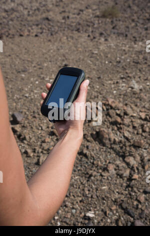 Frau mit einem handheld GPS mit dürren Berge als Hintergrund während einer Wanderung. Konzentrieren Sie sich auf das GPS-Gerät (Garmin Montana 610) Stockfoto