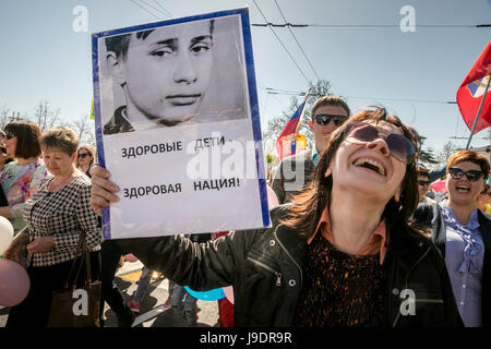 Eine Frau hält ein Porträt des jungen Vladimir Putin mit der Aufschrift "gesunde Kinder - gesunde Nation!" auf der Mai-Demonstration in Sewastopol Stockfoto