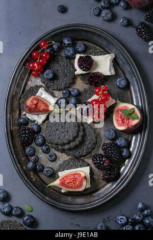 Schwarze Cracker mit Käse und Beeren Stockfoto