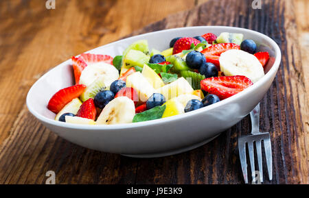 Frische Früchte und Beeren Salat in eine Schüssel geben Stockfoto