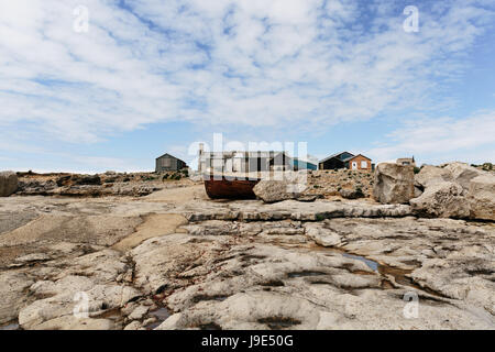 Hölzerne Boot und Strand Fischerhütten neben Portland Bill Leuchtturm auf der Insel Portland, Dorset, gegen blauen Himmel und Wolken auf einem klaren sonnigen da Stockfoto