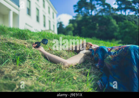 Eine schwangere Frau ist in der Wiese außerhalb eines herrschaftlichen Hauses liegen. Stockfoto