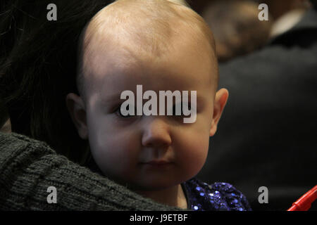 Portrait von Baby Mädchen im Arm der Mutter während einer Veranstaltung Stockfoto