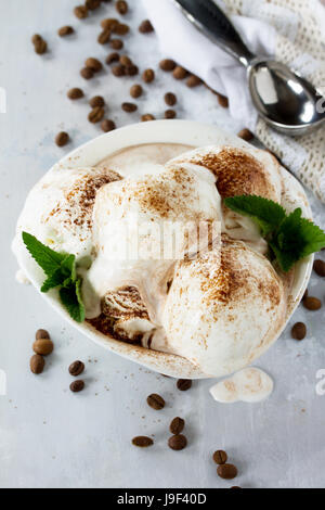 Kugeln aus Creme-Eis mit Schokolade, Minze und Kaffee in einer Schale auf einem Küchentisch aus Marmor. Stockfoto