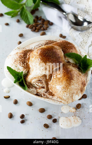 Kugeln aus Creme-Eis mit Schokolade, Minze und Kaffee in einer Schale auf einem Küchentisch aus Marmor. Stockfoto