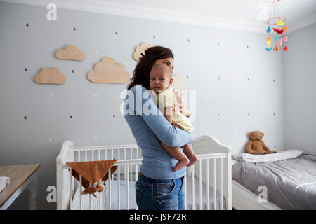 Mutter tröstet neugeborenen Sohn im Kindergarten Stockfoto