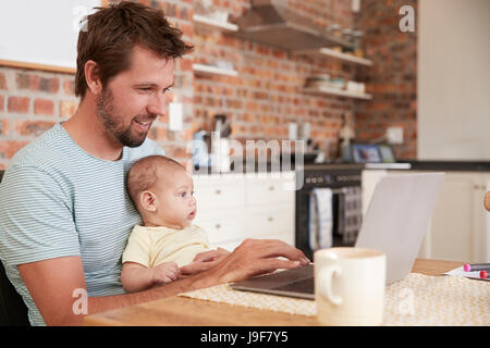 Arbeiten von zu Hause aus auf Laptop mit Baby Sohn Vater Stockfoto