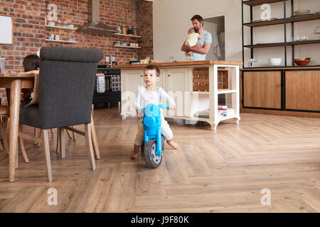 Vater spielt mit Kindern als Mutter arbeiten am Laptop Stockfoto