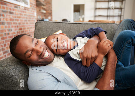 Vater und Sohn gemeinsam auf Sofa kuscheln Stockfoto