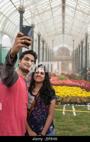 Ein junger Mann nimmt eine Selfie von sich selbst und seinem Freund in den Lal Bagh Botanical Gardens in Bangalore, Karnataka, Indien Stockfoto