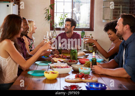 Sechs junge Erwachsene Freunde sitzen am Tisch für eine Dinner-party Stockfoto