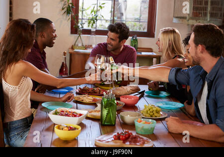 Sechs junge Erwachsene Freunde machen einen Toast auf einer Dinner-party Stockfoto