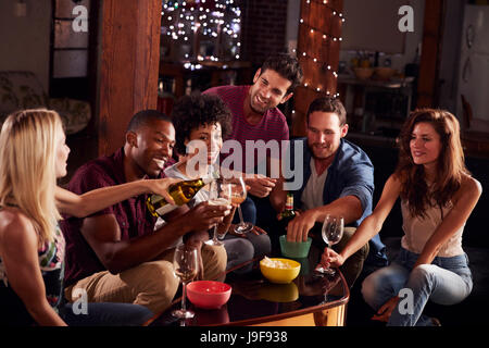 Junge Erwachsene Freunde trinken und Snacks zu Hause essen Stockfoto