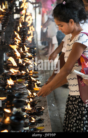 Ein junger Pilger leuchtet eine Öllampe auf den Zahntempel in Kandy, Sri Lanka Stockfoto