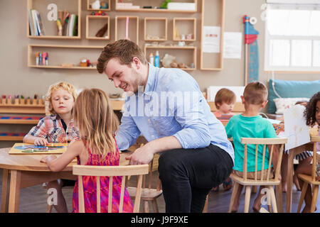 Lehrer und Schüler mit Formen aus Holz In der Montessori-Schule Stockfoto