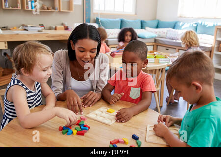 Lehrer und Schüler mit Formen aus Holz In der Montessori-Schule Stockfoto