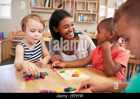 Lehrer und Schüler mit Formen aus Holz In der Montessori-Schule Stockfoto