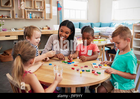 Lehrer und Schüler mit Formen aus Holz In der Montessori-Schule Stockfoto