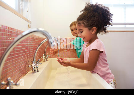 Kinder im Montessori Schule waschen Hände im Waschraum Stockfoto