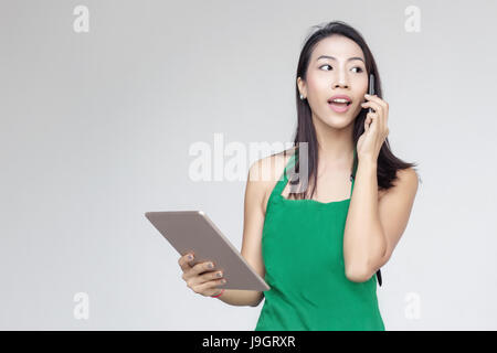 Unternehmertag asiatische Dame beschäftigt mit Mobile und Tablet auf Bestellung verkaufen auf grauem Hintergrund Stockfoto