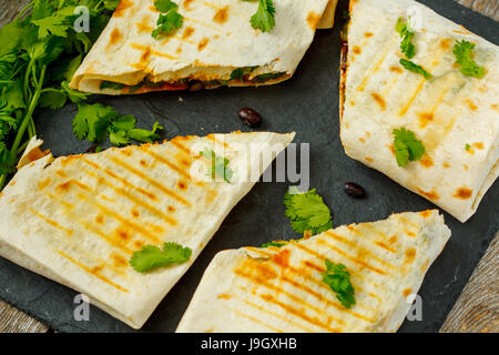 Vegetarische Burritos wraps mit Bohnen, Avocado und Käse auf einer Schiefertafel, Top Sicht. Liebe für eine gesunde vegane Ernährung Konzept Stockfoto