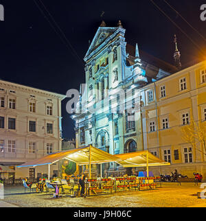 LEMBERG, UKRAINE - 16. MAI 2017: Die riesige Garnisonkirche St. Peter und Paul hinter der überdachten Sommerterrasse des örtlichen Cafés, am 16. Mai in Lemberg. Stockfoto