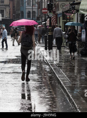 Soho, London, UK. 2. Juni 2017. Eine Frau Rosa Regenschirm ist von der Sonne beschienen, als es durch die Wolken bricht, gelangt nach einer der die Gewitter vorhergesagt durch das Met Office über Old Compton Street in Soho, London. Bildnachweis: Paul Davey/Alamy Live-Nachrichten Stockfoto