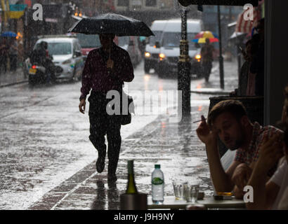 Soho, London, UK. 2. Juni 2017. Ein Mann mit einem Regenschirm geht entlang der Fahrbahn als einer der Gewitter vorhergesagt durch die Met Office Pässe über Old Compton Street in Soho, London. Bildnachweis: Paul Davey/Alamy Live-Nachrichten Stockfoto