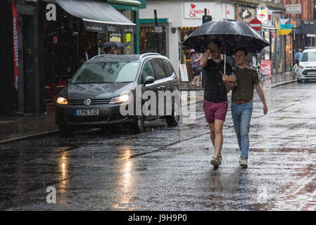 Soho, London, UK. 2. Juni 2017. Zwei Männer teilen einen Regenschirm als einer der Gewitter vorhergesagt durch die Met Office Pässe über Old Compton Street in Soho, London. Bildnachweis: Paul Davey/Alamy Live-Nachrichten Stockfoto