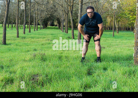 Abstrakt und konzeptionelle müde, müde Mann im Wald. Mann niedergedrückt, ruhen Sie sich nach einem Lauf in den Wald, an einen Baum gelehnt. Stockfoto