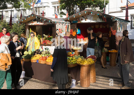 Touristen und einheimische mischen sich auf einem Weihnachtsmarkt in Madeira. Bunte exotische Früchte stehen zum Verkauf. Stockfoto