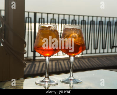 Kellner vorbereitet Aperol Sprits Sommer cocktail mit Aperol, prosecco, Eis-Würfel und Orange im Weinglas, bereit, auf der sonnigen Terrasse mit Meer zu trinken Stockfoto