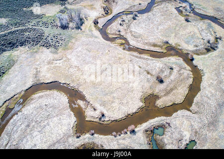 Illinois Fluß schlängelt sich durch Arapaho National Wildlife Refuge, North Park in der Nähe von Walden, Colorado, Vorfrühling Luftbild Stockfoto