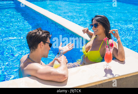 junges Paar aus dem am Rand des Schwimmbades Stockfoto