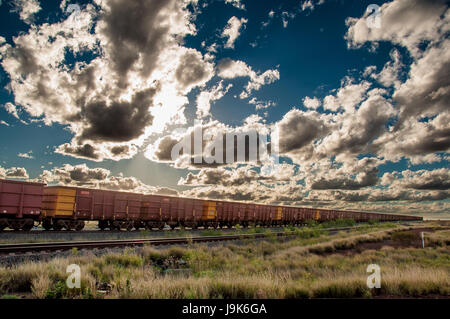 Ein Eisen-Erz-Zug unter einem dramatischen Himmel in der Pilbara-Region von Western Australia. Stockfoto