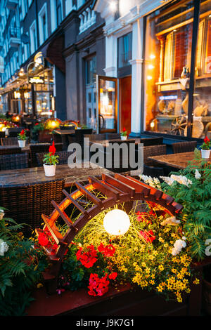 Dekorative Beleuchtung in der Nähe von freien Tische A Street Cafe am Abend oder Nachtbeleuchtung In der alten europäischen Stadt. Stockfoto