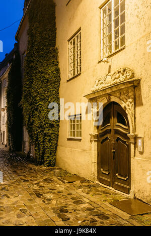 Riga, Lettland. Alte hölzerne braun Tür des Portals, verziert durch Spritzgießen auf der Fassade des alten Gebäudes auf Torna Straße In der Altstadt In der Beleuchtung am Abend O Stockfoto