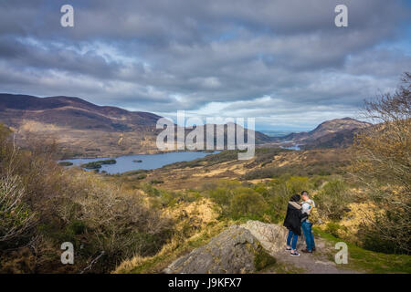 Killarney National Park, Irland - April 2017: Paar Touristen stehen auf einem großen Felsen und die Bilder von den Bergen und Seen in der Kil Stockfoto