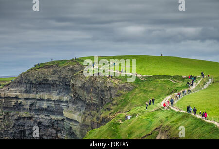 Cliffs of Moher, Irland - April 2017: Menschen zu Fuß auf einem Pfad über die Klippen von Moher an einem trüben, bewölkt und düsteren Tag, Irland Stockfoto