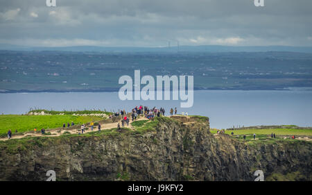 Cliffs of Moher, Irland - April 2017: Menschen zu Fuß auf einem Pfad über die Klippen von Moher an einem trüben, bewölkt und düsteren Tag, Irland Stockfoto