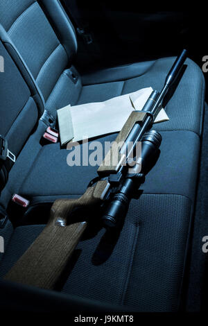 Eine Pistole und Umschlag auf dem Rücksitz eines Autos. Stockfoto