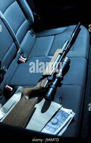 Eine Pistole und Fotos auf dem Rücksitz eines Autos. Stockfoto