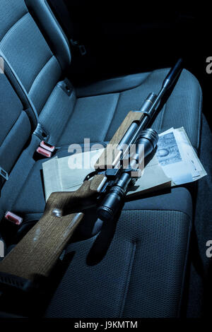 Eine Pistole und Fotos auf dem Rücksitz eines Autos. Stockfoto